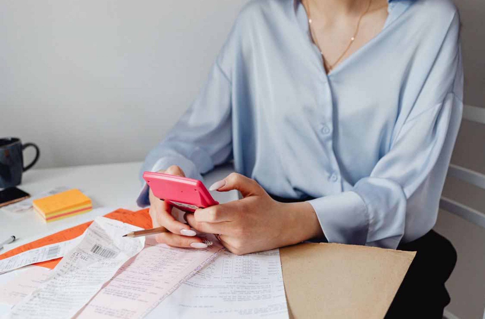 Business owner reviewing receipts and financial records while using a phone, representing cash flow planning and business coaching for SMEs.
